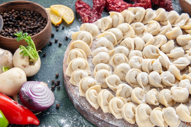 Vooraanzicht van dichtbij kleine rauwe knoedels met bloem en groenten op donker vlees deeg voedsel gerecht calorie maaltijd kleur bak groente