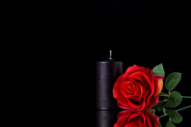 Vooraanzicht van donkere kaars met rode roos op zwarte ondergrond