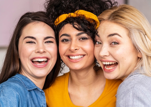 Vooraanzicht van drie gelukkige vrouwen die samen stellen en glimlachen