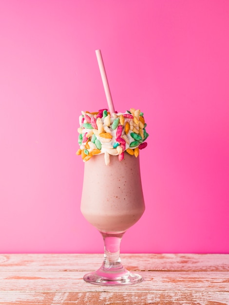 Vooraanzicht van een glas milkshake met roze achtergrond