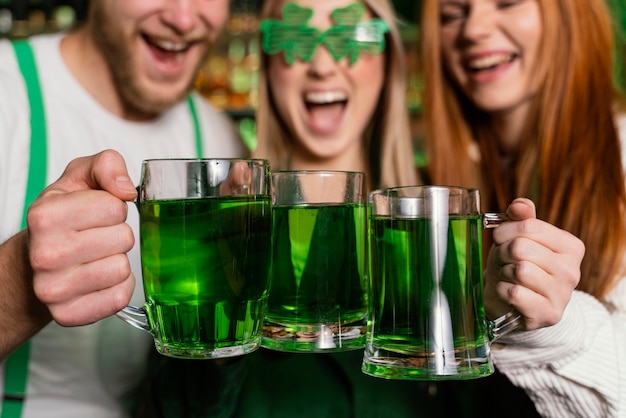 Vooraanzicht van een groep vrienden die st. patrick's day met een drankje aan de bar