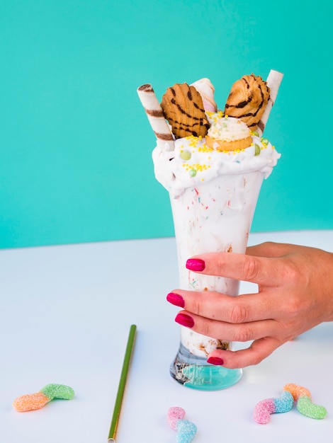 Vooraanzicht van een hand die een glas milkshake houdt