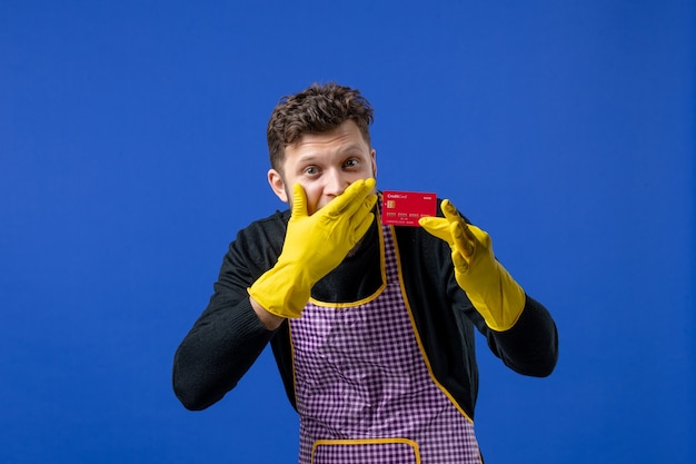 Vooraanzicht van een jonge man die de hand op het gezicht legt met de kaart in de linkerhand op de blauwe muur