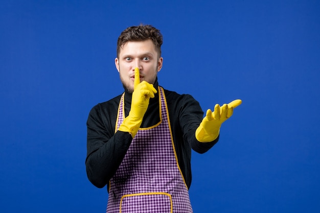 Vooraanzicht van een jonge man die een stilteteken maakt dat op een blauwe muur staat