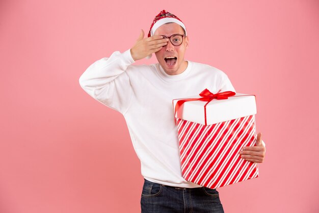 Vooraanzicht van een jonge man met een groot cadeau op de roze muur