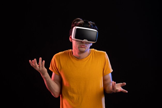 Vooraanzicht van een jonge man met een vr-headset op de donkere muur