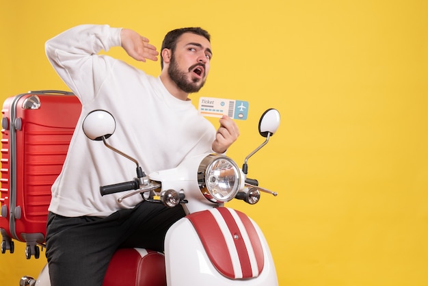Vooraanzicht van een jonge reizende man die op een motorfiets zit met een koffer erop en een kaartje vasthoudt terwijl hij luistert naar de laatste roddels op geïsoleerde gele achtergrond
