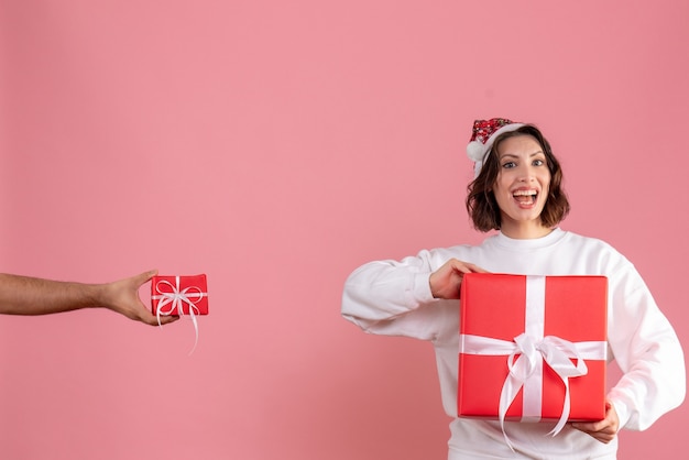 Vooraanzicht van een jonge vrouw die aanwezig is met de man die haar andere cadeau op de roze muur geeft