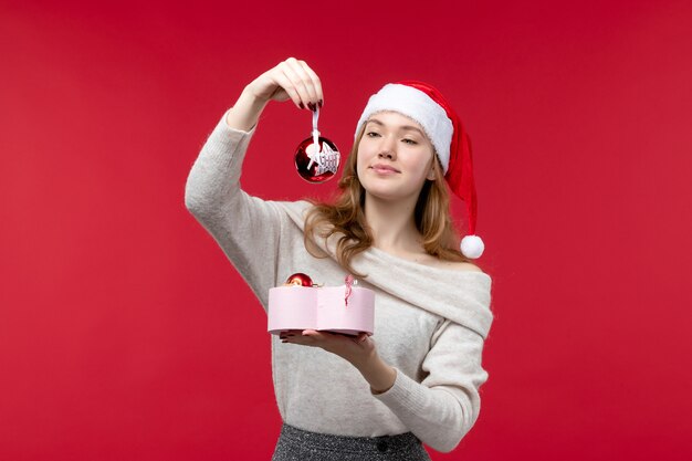 Vooraanzicht van een jonge vrouw die een cadeautje vol speelgoed op rood vasthoudt