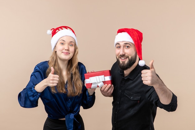 Vooraanzicht van een jonge vrouw met een man die allebei zijn cadeau aan haar vasthoudt op de roze muur