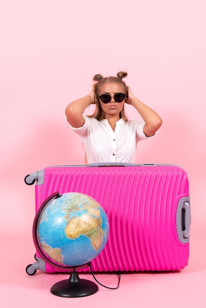 Vooraanzicht van een jonge vrouw met haar roze tas die zich voorbereidt op vakantie op roze muur