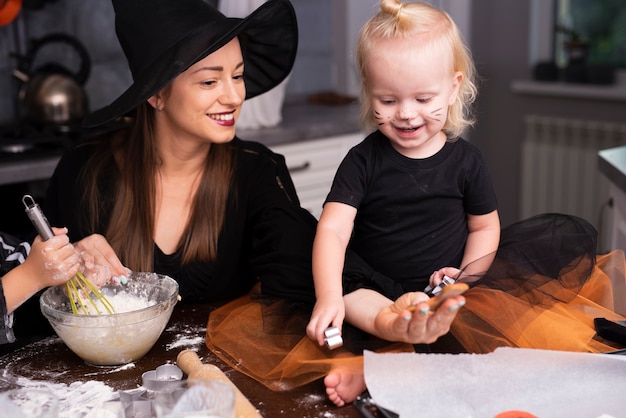 Vooraanzicht van een moeder en haar kinderen die Halloween-koekjes maken
