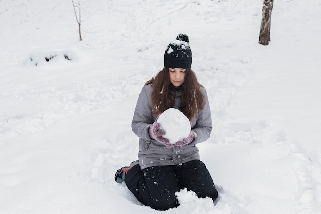 Vooraanzicht van een sneeuwbal van de meisjesholding in de winterlandschap