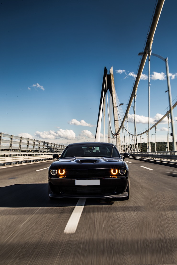 Gratis Foto vooraanzicht van een zwarte sedansportwagen op de brug.