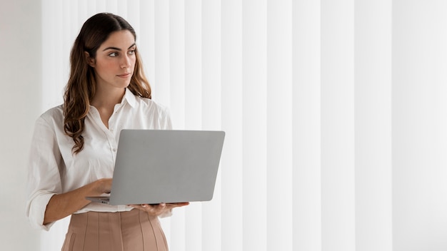 Vooraanzicht van elegante onderneemster die laptop met exemplaarruimte met behulp van