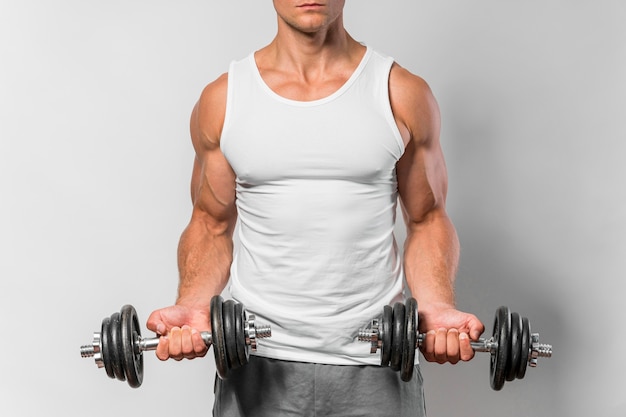 Gratis foto vooraanzicht van fitte man met tanktop die met gewichten traint