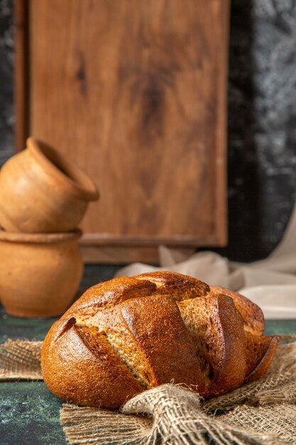 Vooraanzicht van geheel zwart brood op bruine handdoekpotteries op donkere kleurenoppervlakte