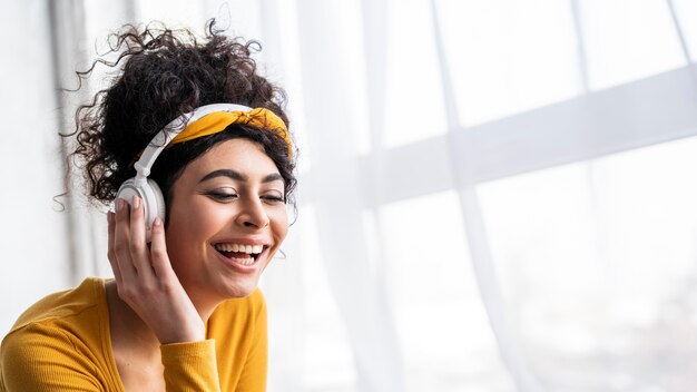 Vooraanzicht van gelukkige vrouw lachen en luisteren naar muziek op koptelefoon met kopie ruimte