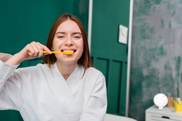 Vooraanzicht van glimlachende vrouw die haar tanden poetst