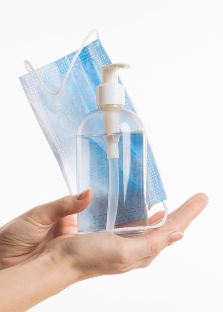 Vooraanzicht van handen met handdesinfecterend middel fles en medisch masker