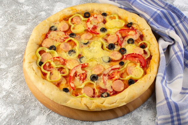 Vooraanzicht van heerlijke kaasachtige pizza met olijvenworsten en tomaten op het grijze bureau