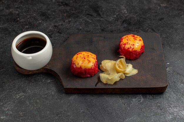 Vooraanzicht van heerlijke sushi visrolletjes met vis en rijstplakken met saus op de grijze muur