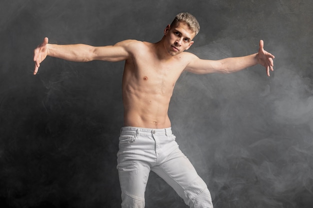 Vooraanzicht van het mannelijke danser stellen in jeans met rook