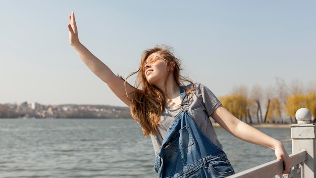 Gratis foto vooraanzicht van het onbezorgde vrouw stellen door het meer