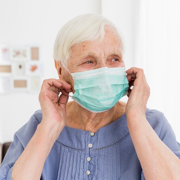 Vooraanzicht van het oudere vrouw stellen met medisch masker