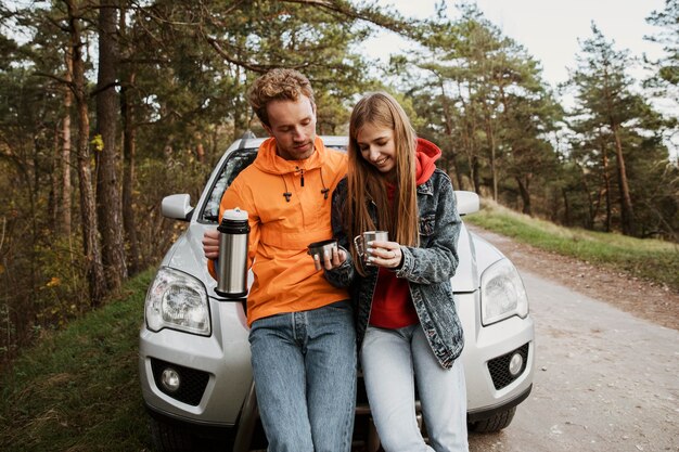 Vooraanzicht van het paar samen op een roadtrip die van warme drank geniet