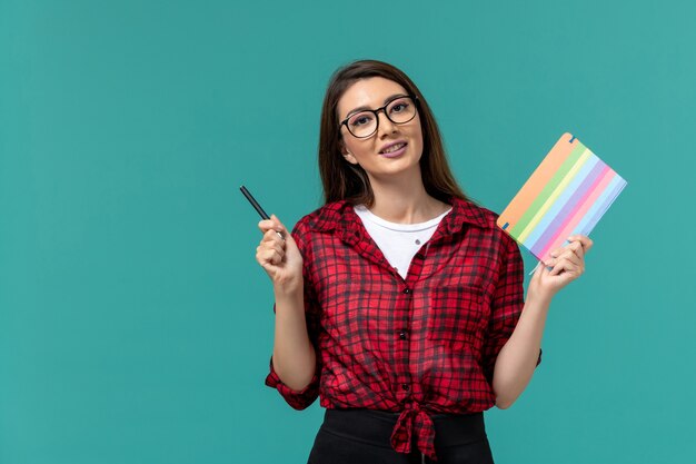 Vooraanzicht van het vrouwelijke voorbeeldenboek en de pen van de studentenholding op de lichtblauwe muur