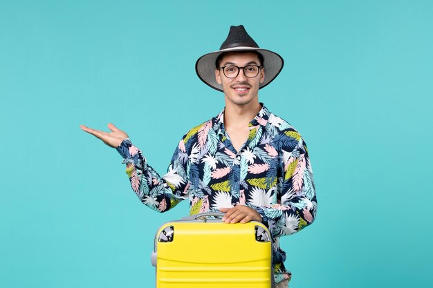 Vooraanzicht van jong mannetje dat met zijn gele zak reis op blauwe muur voorbereidingen treft