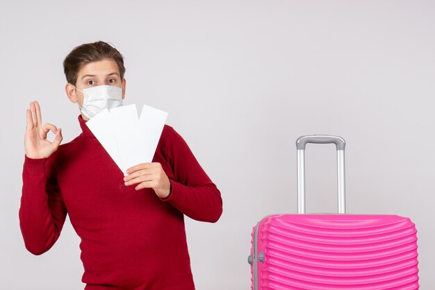 Vooraanzicht van jong mannetje in de vliegtuigkaartjes van de maskerholding op de witte muur