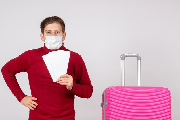 Vooraanzicht van jong mannetje in de vliegtuigkaartjes van de maskerholding op de witte muur