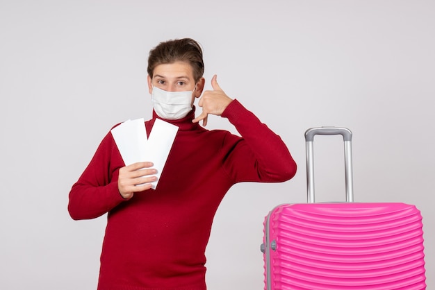 Vooraanzicht van jong mannetje in de vliegtuigkaartjes van de maskerholding op de witte muur