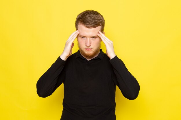 Vooraanzicht van jong mannetje in zwart overhemd die en hoofdpijn stellen hebben