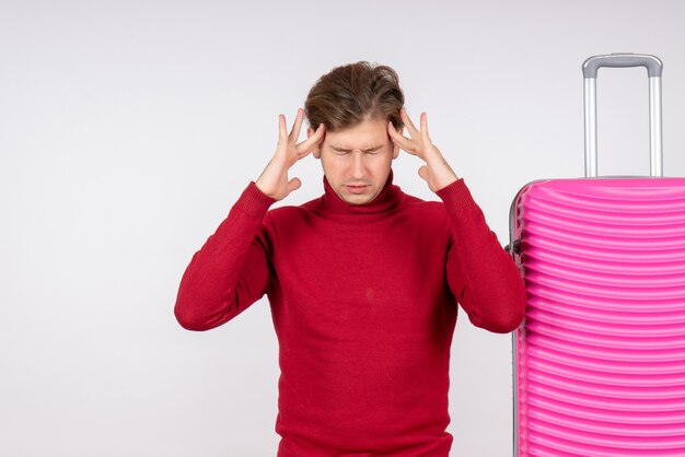 Vooraanzicht van jong mannetje met roze zak die hoofdpijn op witte muur hebben