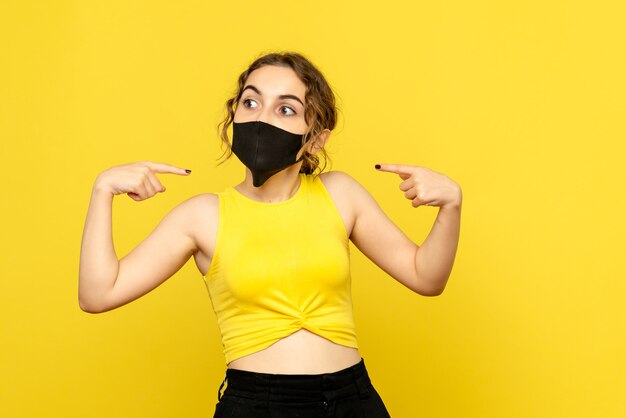 Vooraanzicht van jong meisje in steriel masker op gele muur