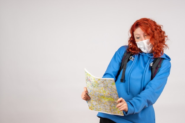 Vooraanzicht van jong wijfje met rugzak en kaart in masker op witte muur