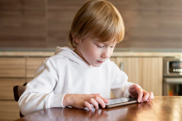 Vooraanzicht van jonge jongen met behulp van smartphone aan de tafel