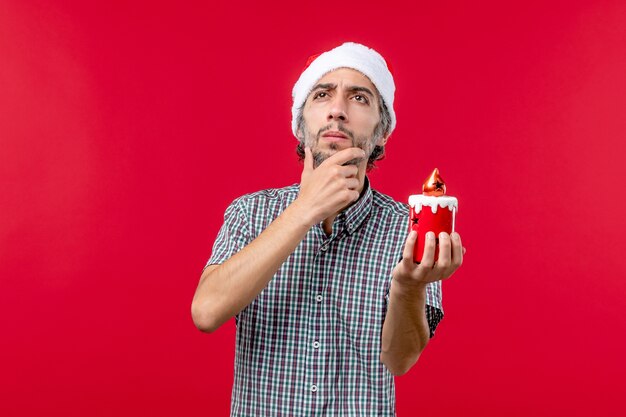 Vooraanzicht van jonge man die weinig speelgoed op rood houdt