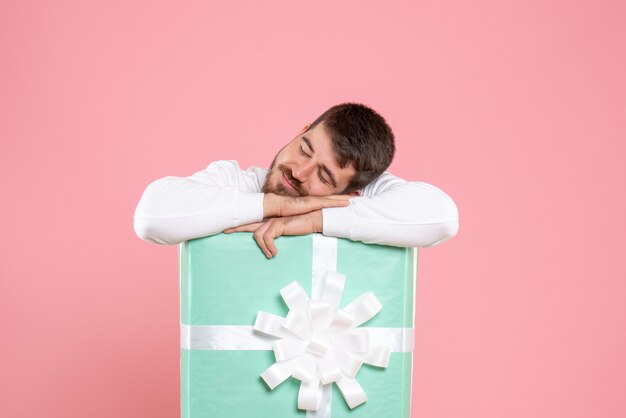 Vooraanzicht van jonge man in huidige doos slapen op roze muur