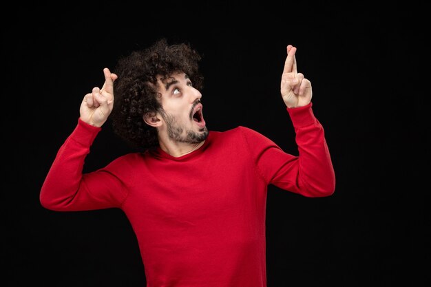 Vooraanzicht van jonge man in rood shirt op zwarte muur