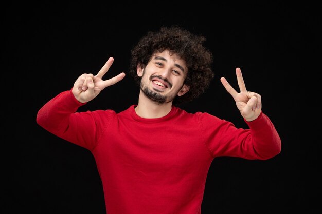 Gratis foto vooraanzicht van jonge man in rood shirt op zwarte muur