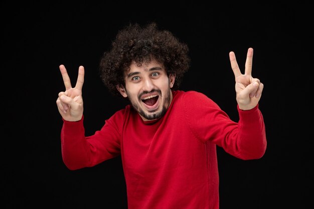 Vooraanzicht van jonge man in rood shirt op zwarte muur