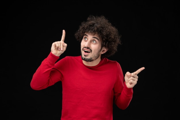 Vooraanzicht van jonge man in rood shirt op zwarte muur