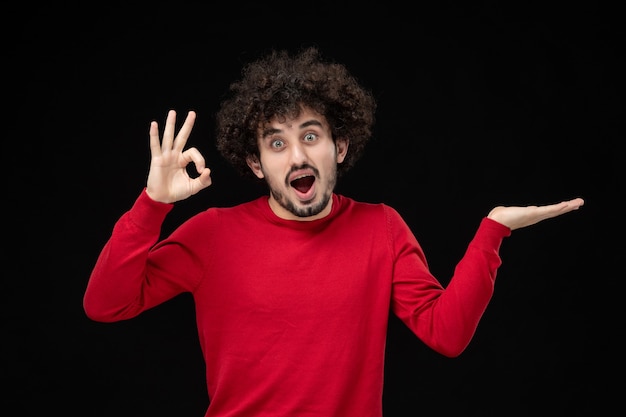 Vooraanzicht van jonge man in rood shirt op zwarte muur