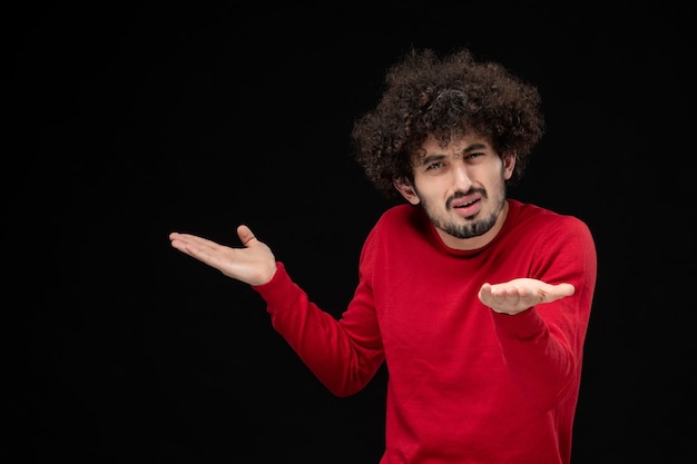 Vooraanzicht van jonge man in rood shirt op zwarte muur