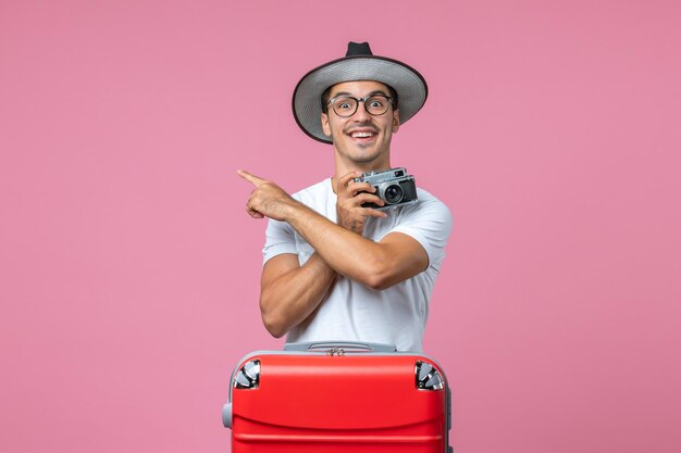 Vooraanzicht van jonge man in zomervakantie die foto's maakt met camera op de roze muur