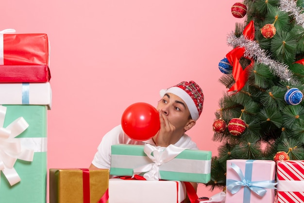 Vooraanzicht van jonge man kerst vieren rond presenteert op roze muur